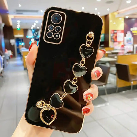 a woman holding up a phone case with heart charms