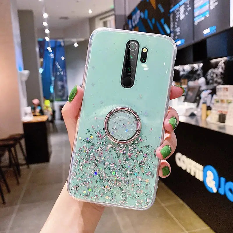 a woman holding a phone case with glitter and a ring