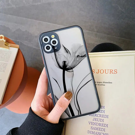 a woman holding a phone case with a black and white flower