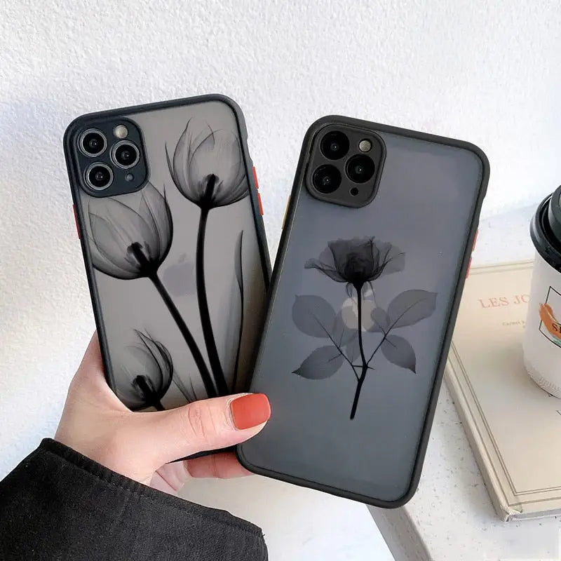 a woman holding a phone case with a black flower design
