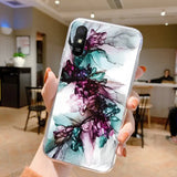 a woman holding up a phone case with a painting on it