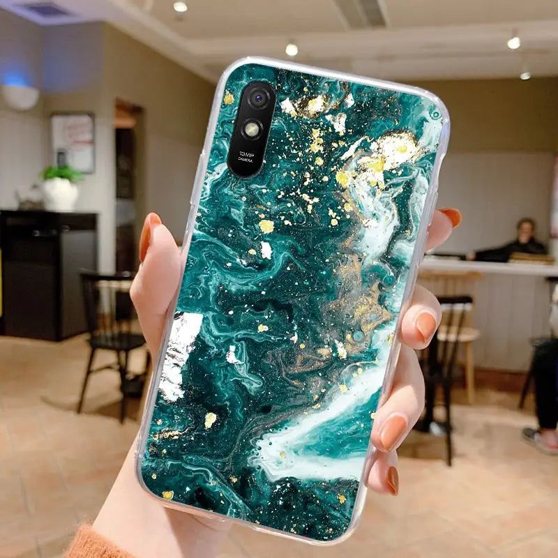 a woman holding up a phone case with a green marble pattern