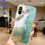 a woman holding up a phone case with a bird on it