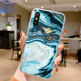 a woman holding up a phone case with a blue and gold marble pattern