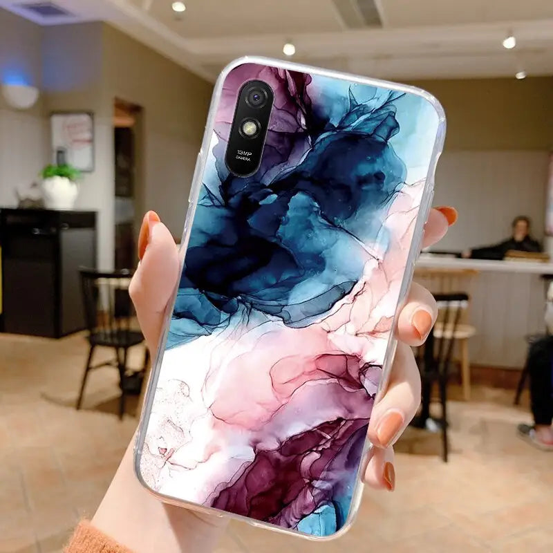 a woman holding up a phone case with a colorful marble pattern