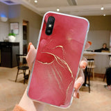 a woman holding a red phone case with gold glitter