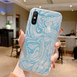 a woman holding up a phone case with a marble pattern