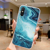 a woman holding up a phone case with a blue marble pattern