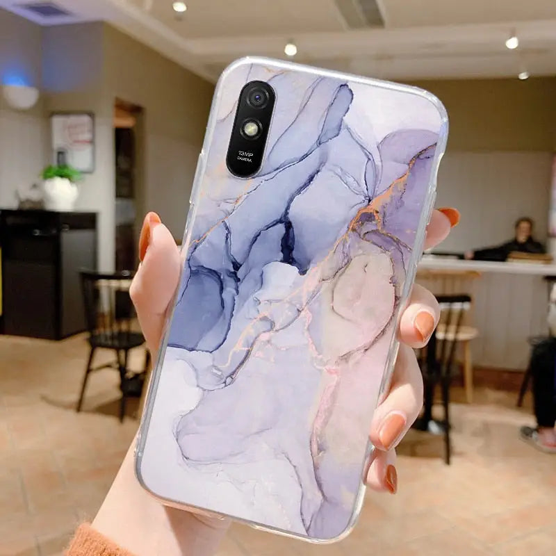 a woman holding up a phone case with a marble pattern