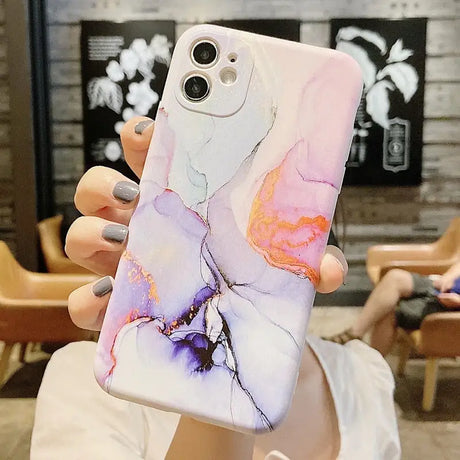 a woman holding a phone case with a marble pattern