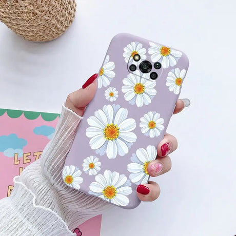 a woman holding a phone case with white flowers on it