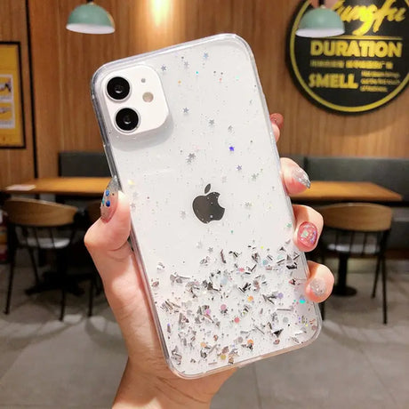 a woman holding a phone case with glitter and stars