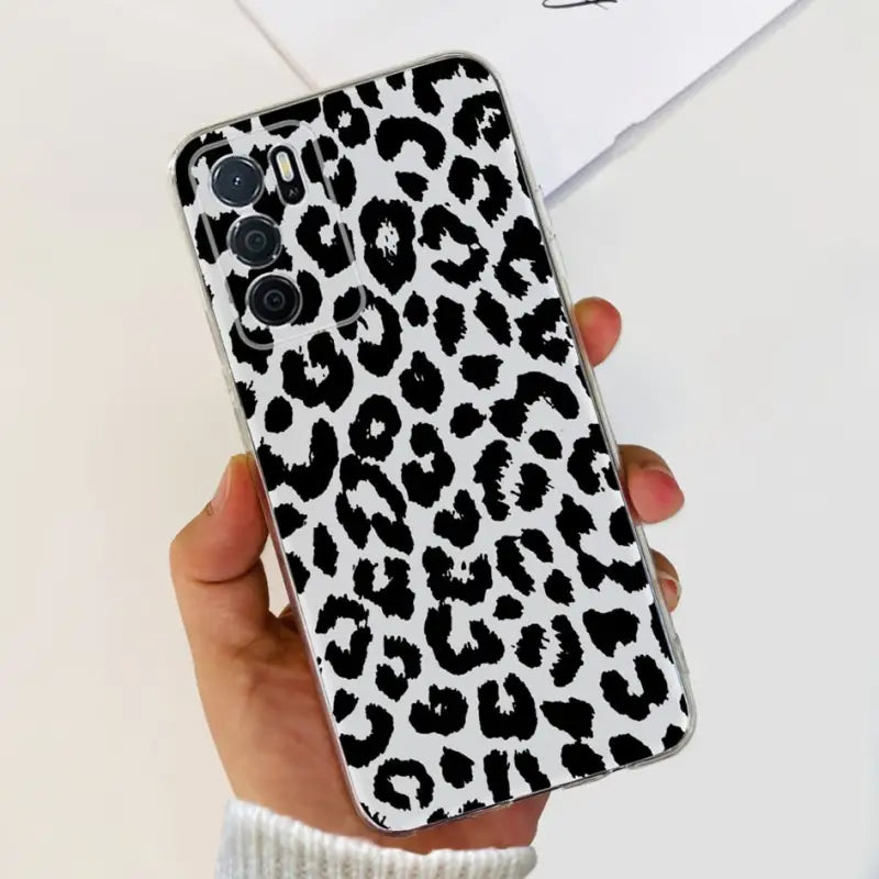 a woman holding a phone case with a black and white leopard print