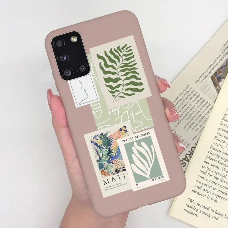 a woman holding a phone case with a book and a plant