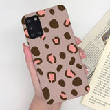 a woman holding a phone case with a pink and brown leopard print