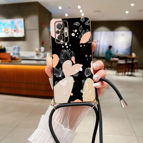 a woman holding a phone case with a black and white floral design