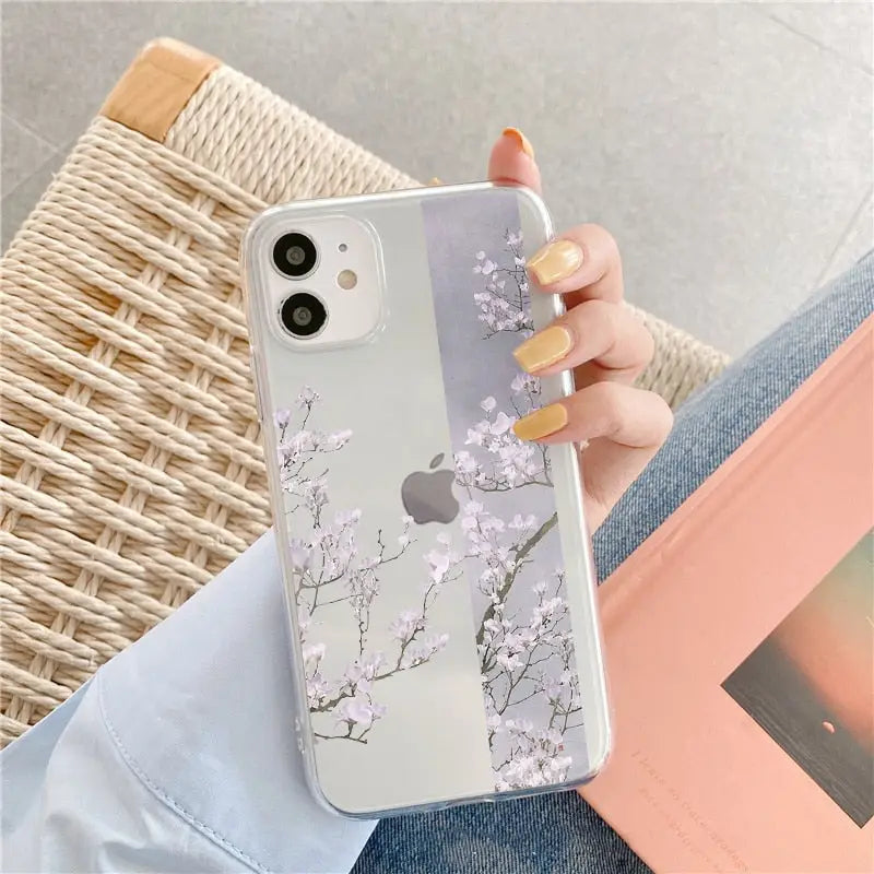 a woman holding a phone case with a white flower on it