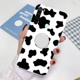 a woman holding a phone case with a cow pattern