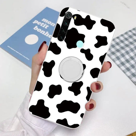 a woman holding a phone case with a cow pattern