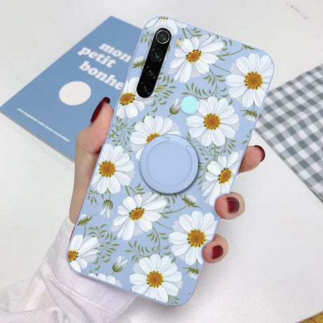 a woman holding a phone case with white flowers on it