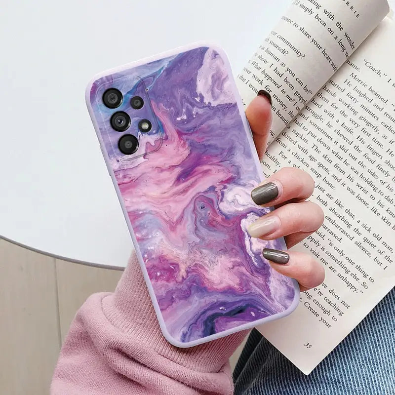 a woman holding a purple marble phone case