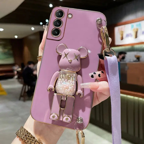 a woman holding a phone case with a pink bear