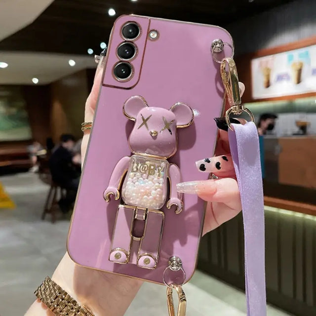 a woman holding a phone case with a pink bear