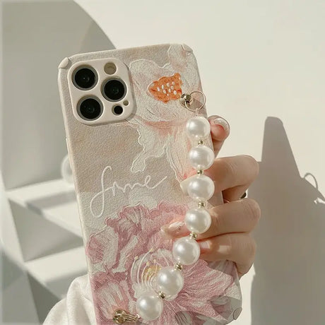 a woman holding a phone case with pearls and flowers