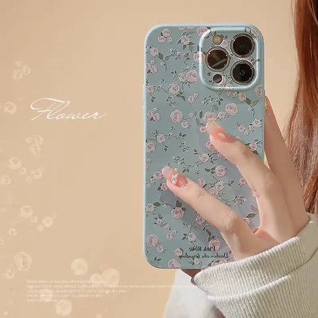 a woman holding a phone case with flowers on it