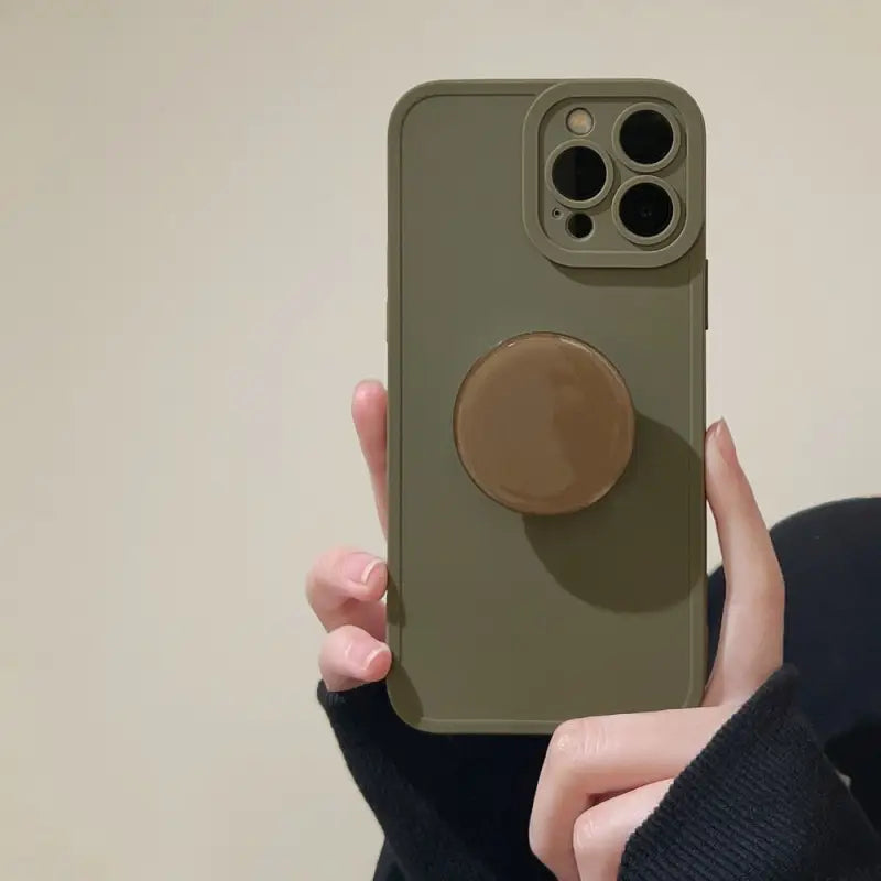 a woman holding a phone case with a circular button