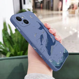 a woman holding a phone case with a blue whale on it