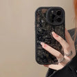 a woman holding a phone case with a black and white marble pattern