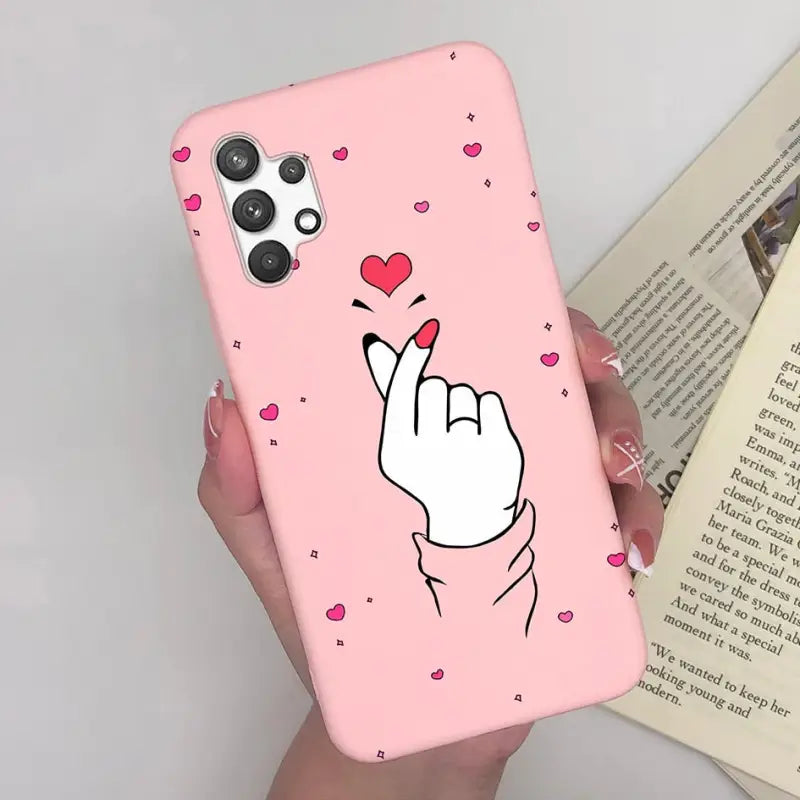 a woman holding a pink phone case with a heart on it