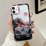 a woman holding a phone case with mountains in the background