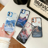 a woman holding a phone case with mountains on it