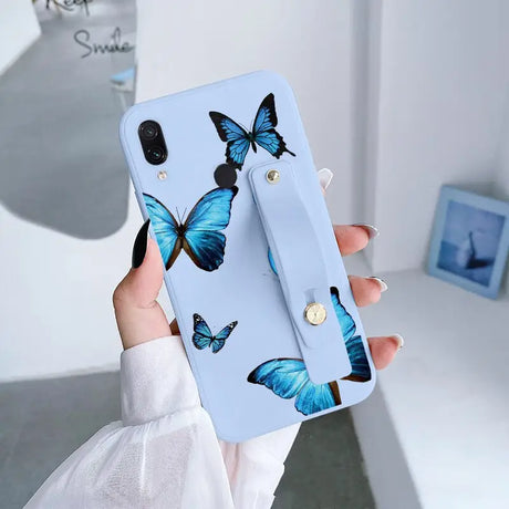 a woman holding a phone case with blue butterflies on it