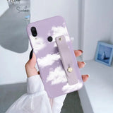 a woman holding a phone case with clouds on it