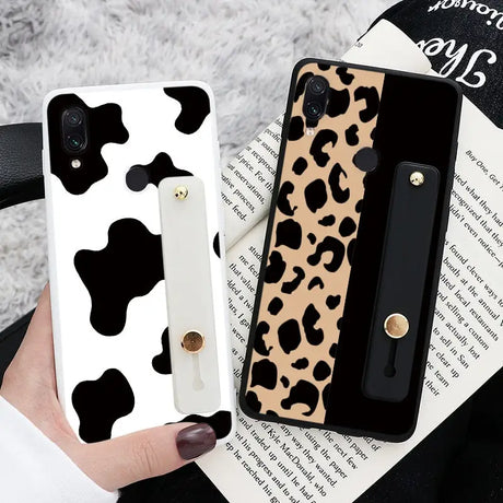 a woman holding a phone case with a cow print