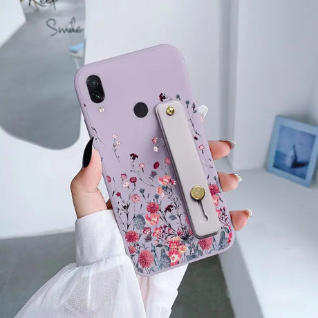 a woman holding a phone case with flowers on it