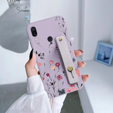 a woman holding a phone case with flowers on it