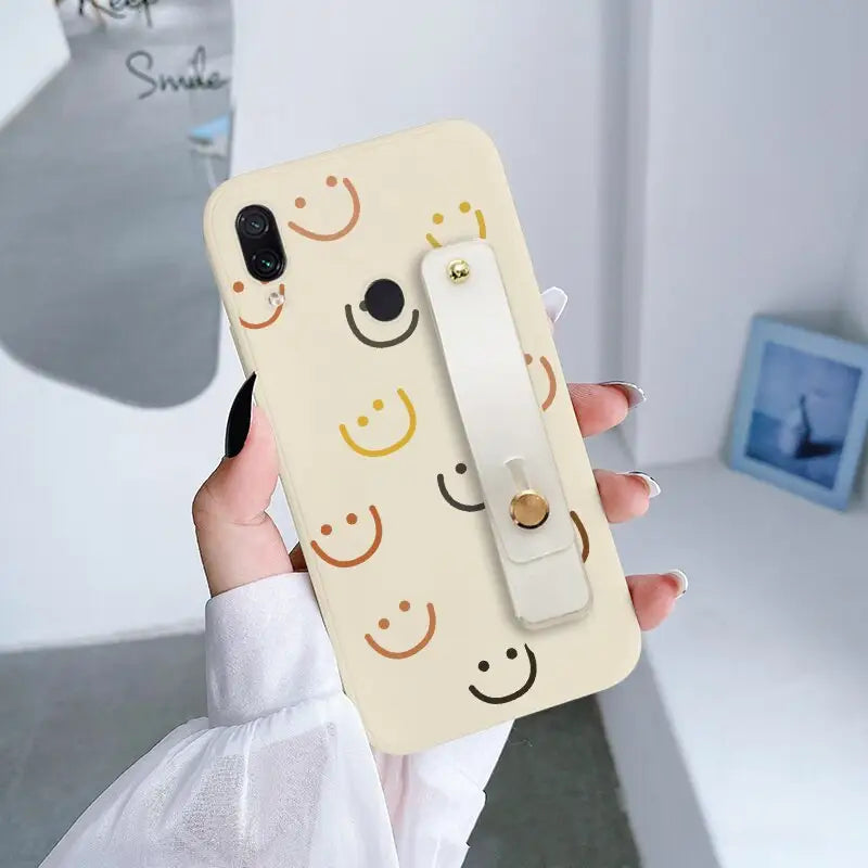 a woman holding up a phone case with a smiley face on it