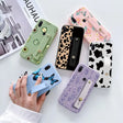 a woman holding a phone case with a cow pattern