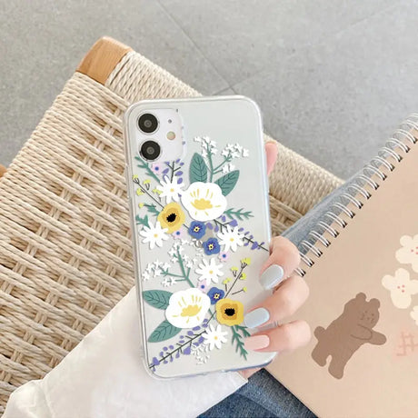 a woman holding a phone case with flowers on it