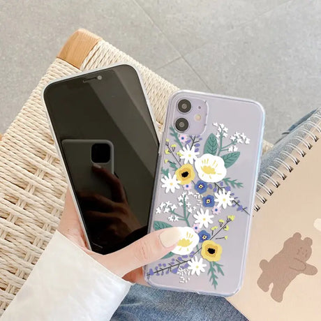 a woman holding a phone case with flowers on it