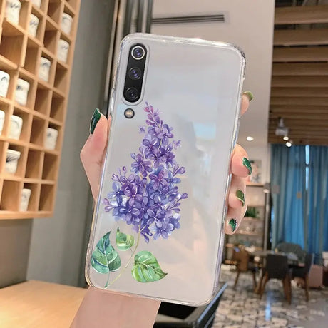 a woman holding a phone case with purple flowers on it