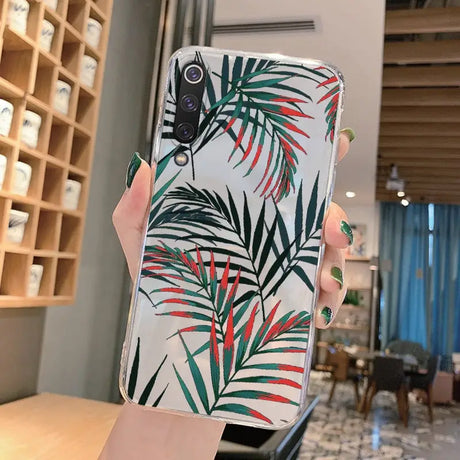 a woman holding up a phone case with a tropical print