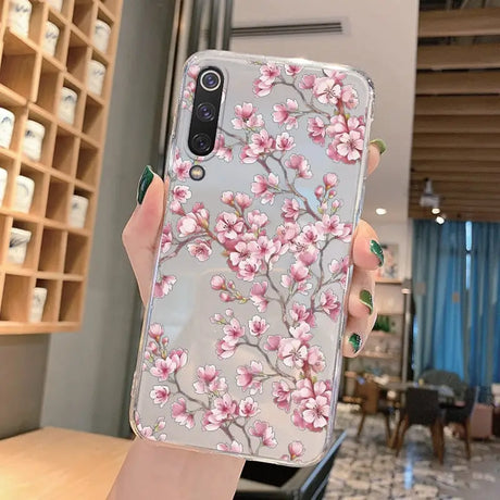 a woman holding a phone case with pink flowers on it