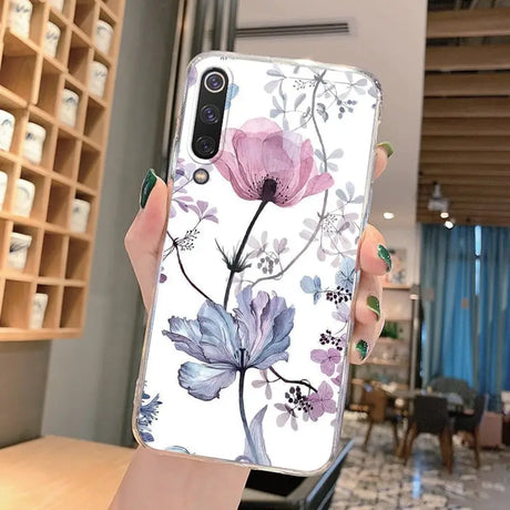 a woman holding up a phone case with flowers on it