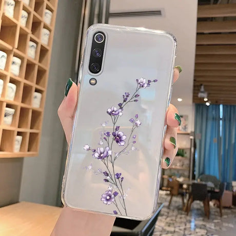 a woman holding a phone case with purple flowers on it