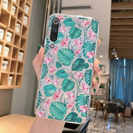 a woman holding up a phone case with a tropical print